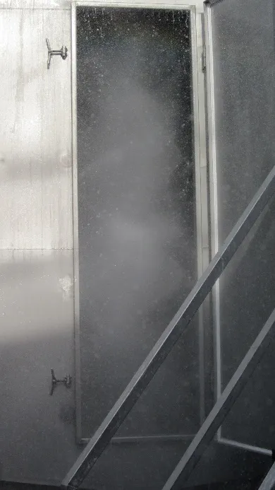 Fine spray mist inside an open-spray column, seen through an open inspection door